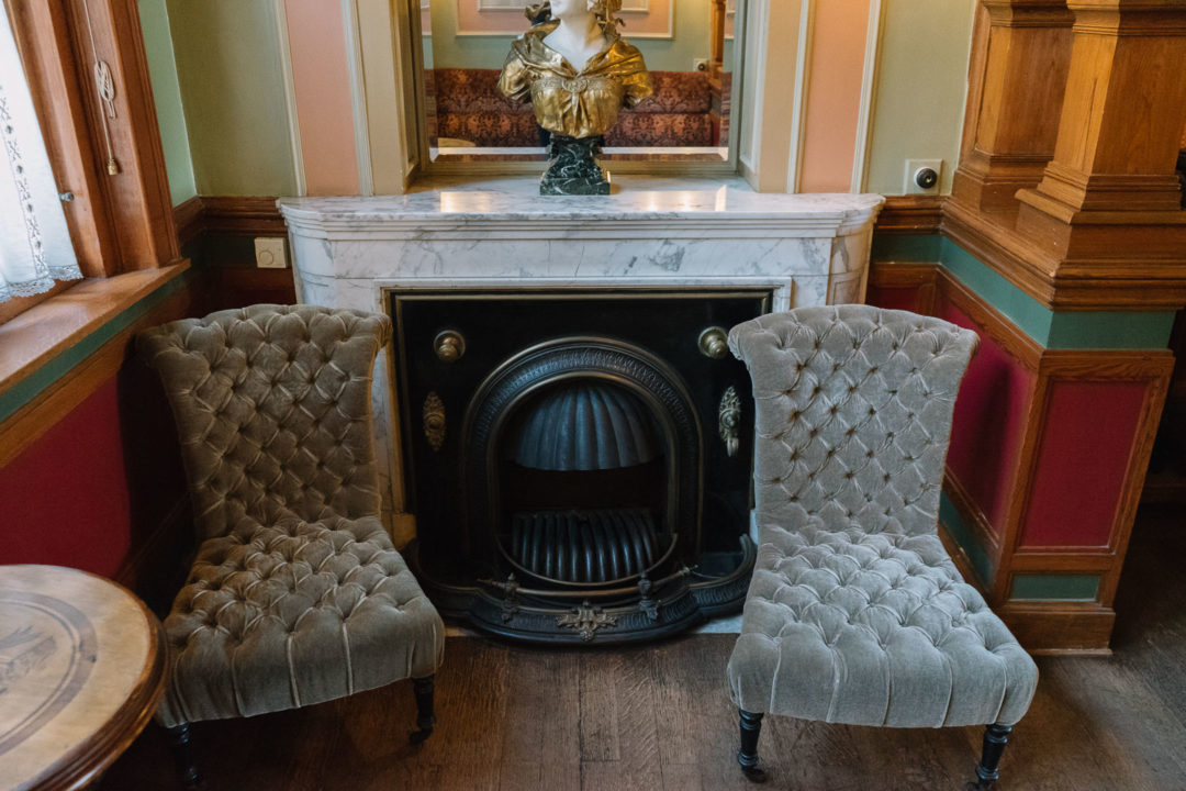 Antique fireplace and two velvet armchairs at Maison Autrique
