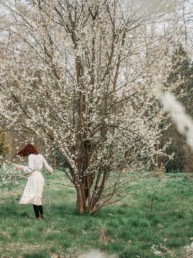 Girl spinning next to a blossoming tree