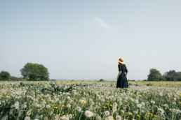 Girl with a hat standing in a field of dandelions