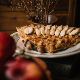 Slice of apple pie next to apples