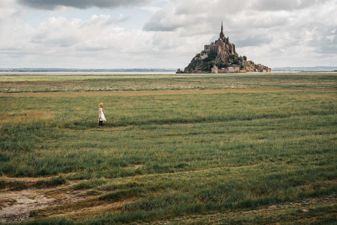Mont Saint-Michel in the distance, girl in a dress in the foreground