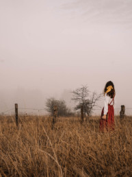 Girl standing in the middle of an empty and foggy field