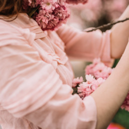 A girl in a pink dress entangled in pink cherry blossoms