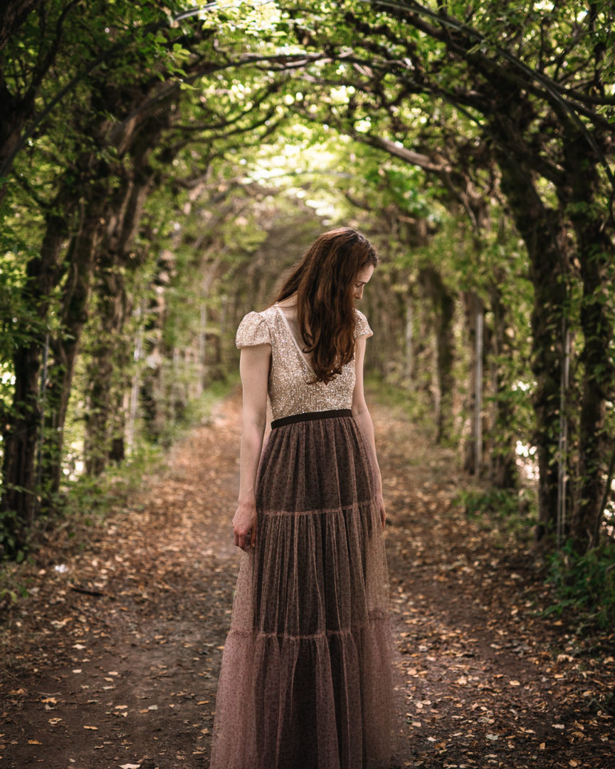 Girl wearing a madame shoushou dress under a tree tunnel