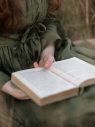 Close-up of a woman holding a book while sitting in the grass