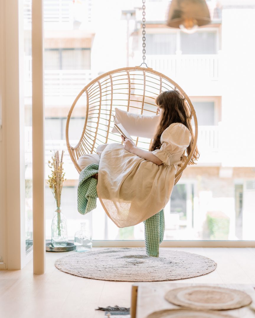 woman reading a book in a hanging egg chair