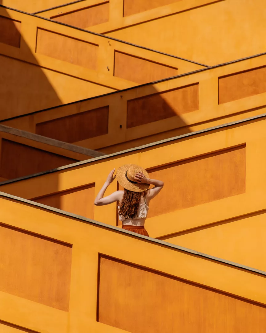 woman holding onto a hat on menton stairs