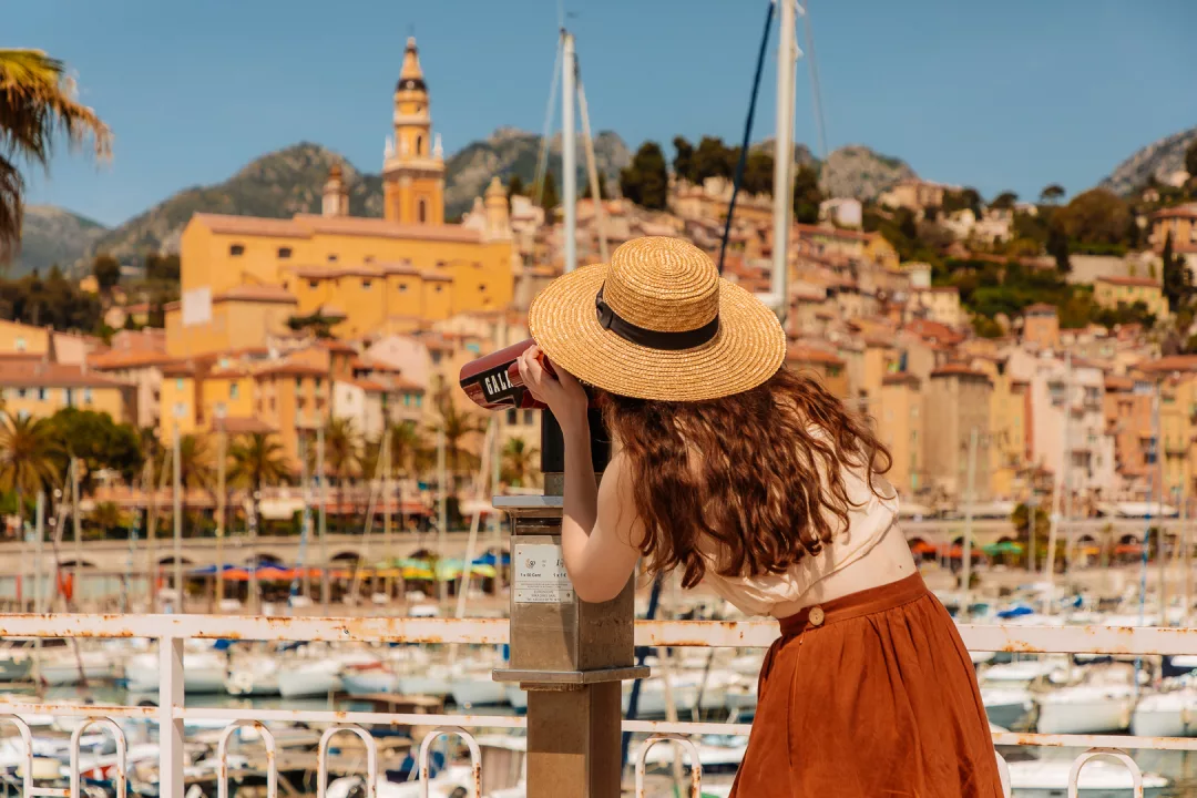 woman using a binocular telescope for a view of menton