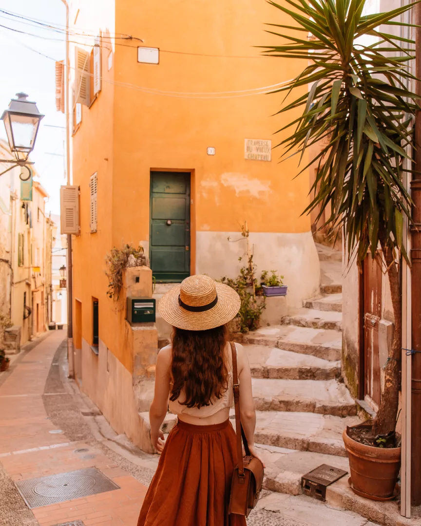 woman walking down the colorful streets of menton